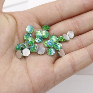 Detailed view of 6mm green fish scale resin cabochons held in palm for scale