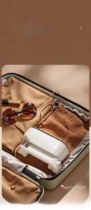 Foldable handheld garment steamer in ivory white stored in a suitcase for travel