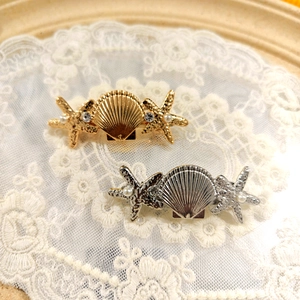 Golden and silver shell hair clips with starfish pearl accents on lace background