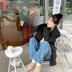 Brown corduroy tote bag with black smiley patterns held by a woman in a cafe