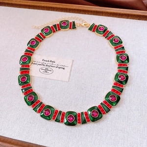 Dettaglio di una collana vintage dorata con smalto verde e pietre rosso rubino