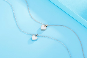 Détails de médaillons cœur argent et or rose avec nacre sur un fond bleu éclatant