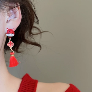 Close-up of red and gold Chinese zodiac tassel earrings with Fu character charm