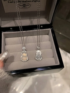 Macro view of stainless steel hulu pendants with jade and cutout mesh in a gift box
