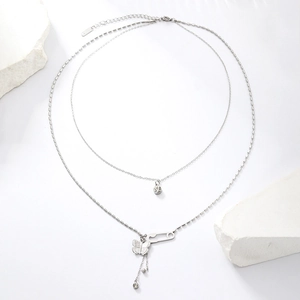 Detail of silver double layer necklace with butterfly, safety pin and zircon pendants