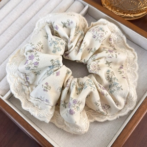 Close-up of beige floral hair scrunchie with lace trim in a wooden jewelry box