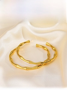 Dettaglio di due bracciali rigidi in bambù placcati oro 18 carati su tessuto seta