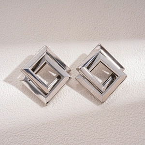 Detail of silver geometric interlocking square earrings with polished metallic finish