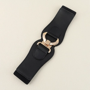 Detail of black wide elastic waist belt featuring a polished gold geometric metal buckle