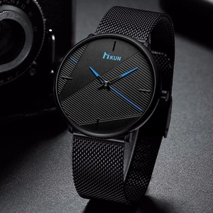 Detail of black quartz watch with mesh strap, blue hands and KUN logo on a vintage camera