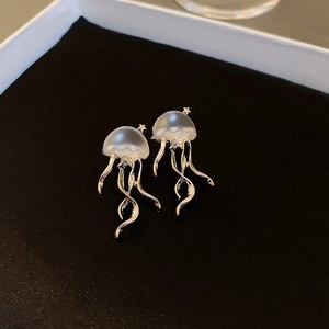 Vista macro di orecchini a medusa creativi con tentacoli argentati e cupola lattea