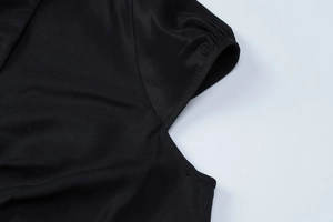 Detailed view of sleeve cuffs and armhole stitching on a black short sleeve top