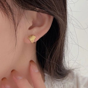 Primo piano di orecchini a conchiglia dorati minimalisti con strisce verticali