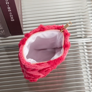 Detail view of pink plush cosmetic bag with gold zipper and white fabric lining