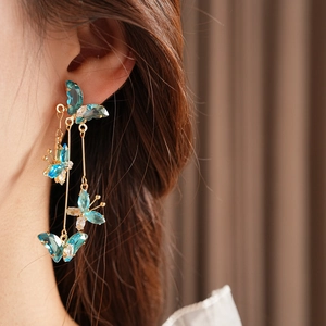 Gros plan de boucles d'oreilles papillon en cristal bleu portées par un mannequin