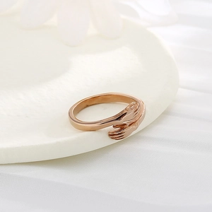 Minimalist rose gold stainless steel hugging hands open ring on white ceramic plate
