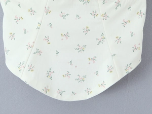 Detailopname van de crèmekleurige bloemenprint top met kant en een ronde zoomlijn