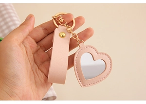 Detail of pink PU leather heart mirror keychain with gold hardware held in hand