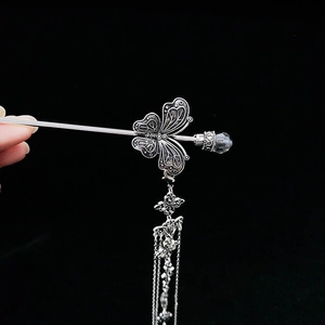 Détail du pic à cheveux papillon en argent antique avec fines chaînes et glands
