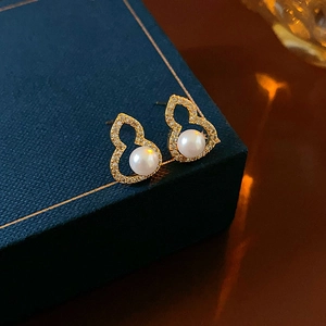 Gold plated gourd pearl stud earrings with sparkling cubic zirconia on a jewelry box