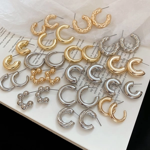 Detailed close-up of C-shaped hoop earrings with hammered, twisted, and beaded designs