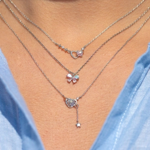 Close-up of layered silver necklaces with heart, star and planet opal pendants