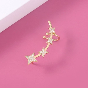 Detail of gold star ear cuff clip with sparkling crystals on pink background