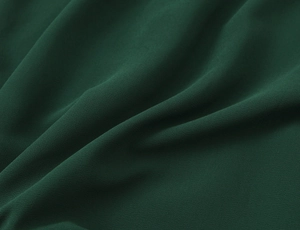 Close-up of deep green textured fabric with soft matte finish and elegant drape