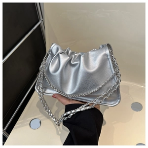 Close-up of silver pleated dumpling bag with metallic texture and chunky chain strap