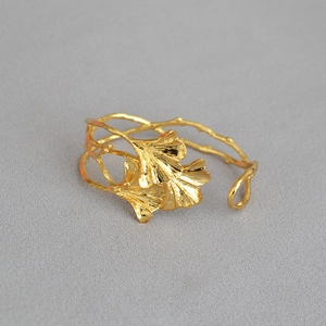 Nahaufnahme der goldenen Ginkgo-Armspange mit gebürsteter Zweigtextur und Metallfinish