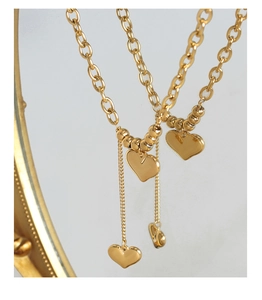 Détail d'un collier doré avec pendentifs cœurs et grosse chaîne en acier titane 18K