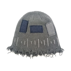 Graue Strickmütze mit Denim-Patches, ausgefranstem Rand und weißen Handnähten im Detail