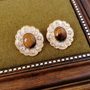 Dettaglio di orecchini a fiore vintage con pietra occhio di tigre e cristalli brillanti