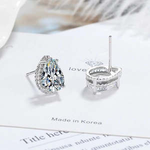 Silver pear-cut zircon stud earrings on a white card with soft feather background