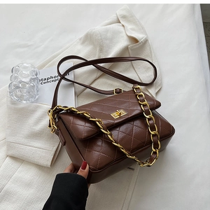 Detail of dark brown quilted PU leather bag with gold chain and metal twist lock closure