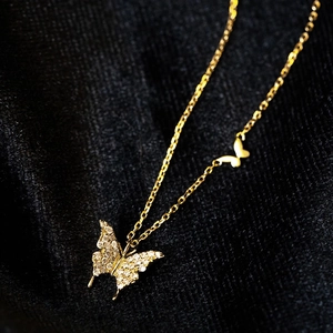 Detalle del collar con colgante de mariposa dorada y piedras de circón blanco