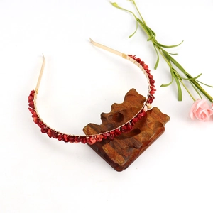 Detail of handmade gold wire headband with red crystal stones on a wooden stand