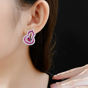 Close-up of model wearing silver gourd earrings with pink oval gemstones and zircons
