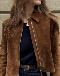 Detail of a brown suede jacket featuring a metallic zipper and classic lapel collar