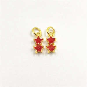 Close-up of golden star-shaped pendants with red cubic zirconia for jewelry DIY making