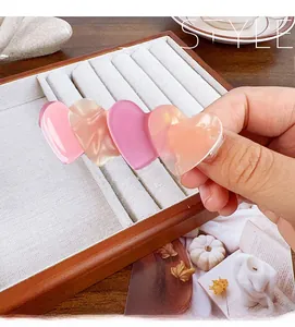 Detailed close-up of premium acetate heart-shaped hair clip with pink and champagne colors