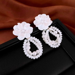 Détail macro de boucles d'oreilles fleur blanche avec pendentifs perles sur cuir noir