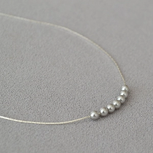 Detailed close-up of 7 minimalist grey pearls on a gold-plated brass necklace chain