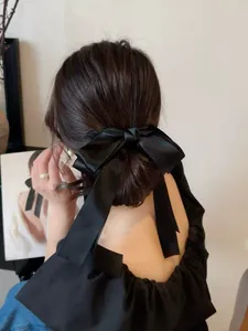 Détail d'un grand nœud en satin noir avec de longs rubans sur l'arrière de la tête