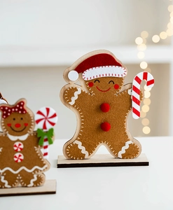 Felt gingerbread man Christmas tabletop decor with wooden base and warm bokeh lighting