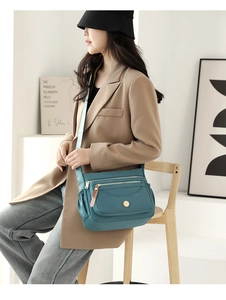Detail of waterproof nylon crossbody bag with multi-layer zippers and side pockets