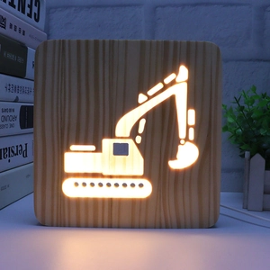 Detail of wooden night light with excavator carving and warm LED glow on a desk