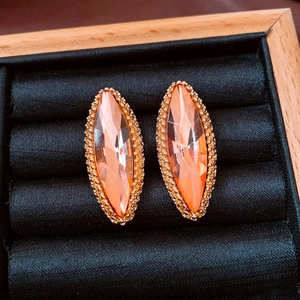 Macro shot of marquise orange crystal earrings with golden beaded edges in a box