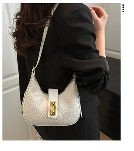 Close-up of a white woven crescent bag with a gold metal buckle on a shoulder strap