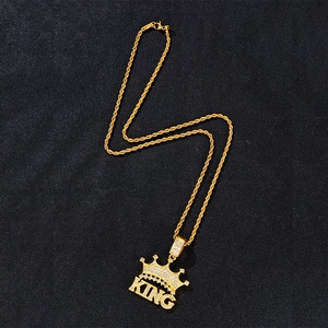 Gold crown KING pendant necklace with clear crystals on a black textured background